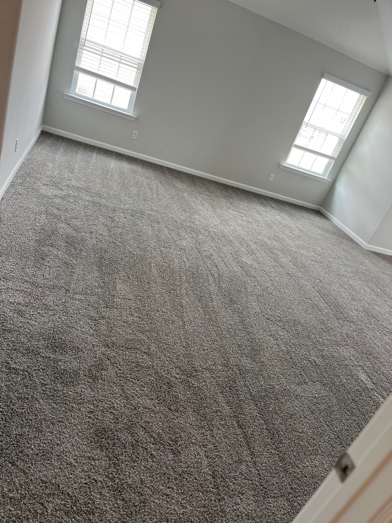 Wall-to-wall gray carpet installed in a large empty rental room